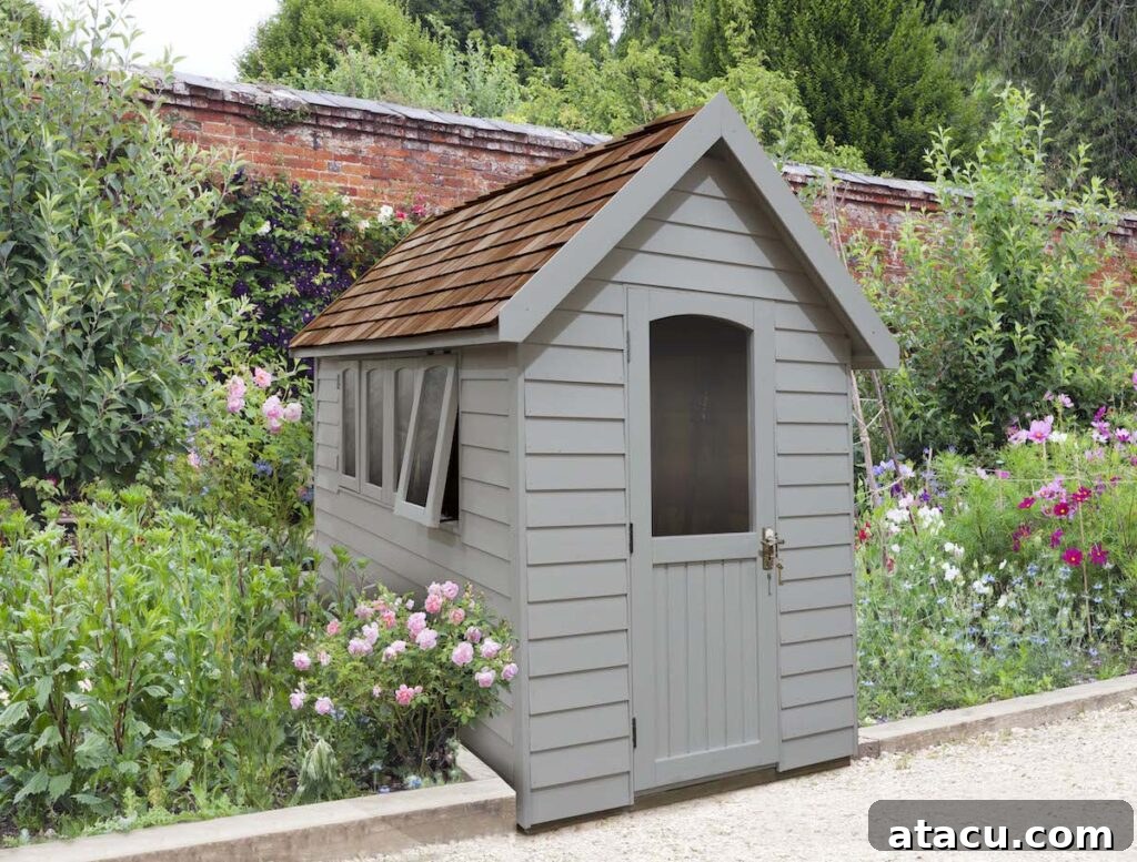 A grey garden shed in a romantic garden with pink roses.