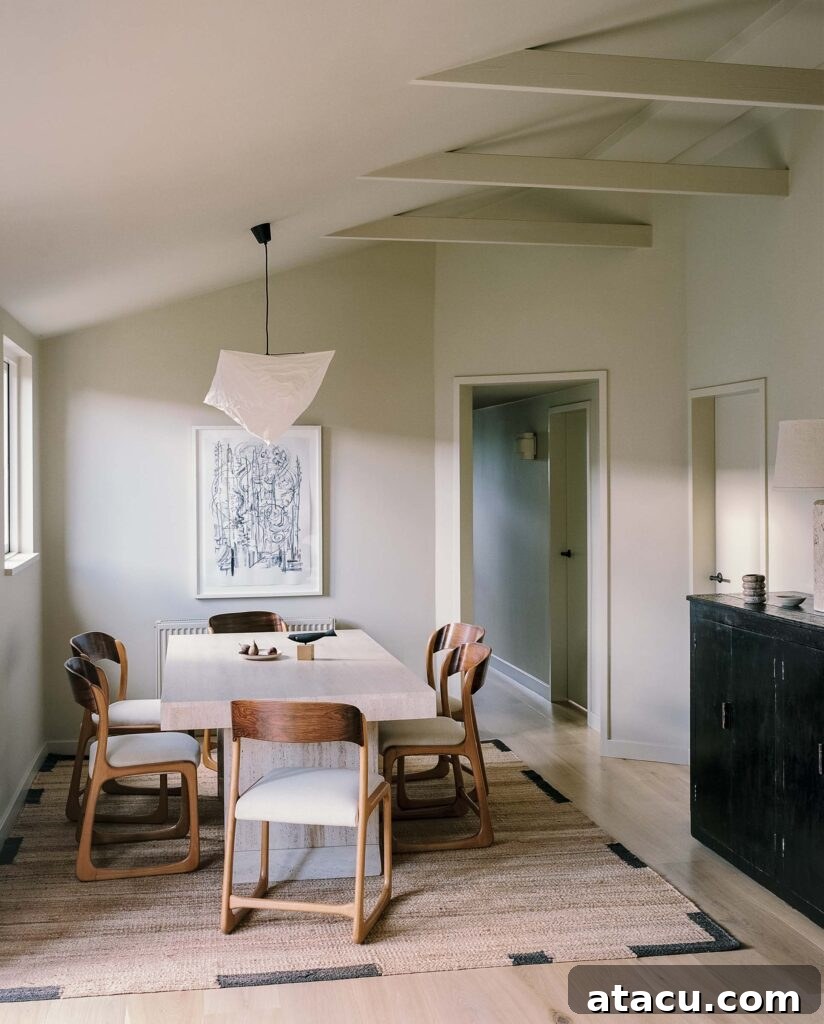 Modern dining room with wood chairs, travertine table, and neutral tones.