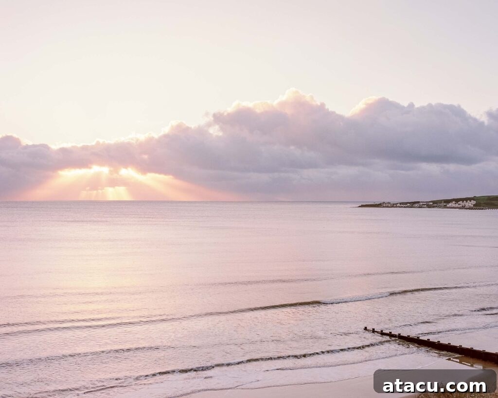 Sunrise over calm sea with light rays through clouds.