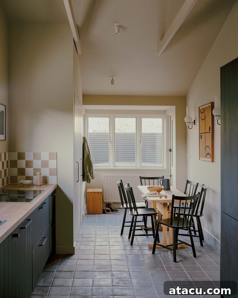 Modern galley kitchen with tile floors and wooden dining table.