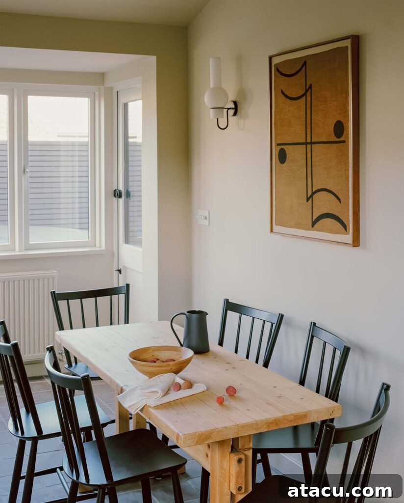 Wood dining table with black chairs and abstract wall art.