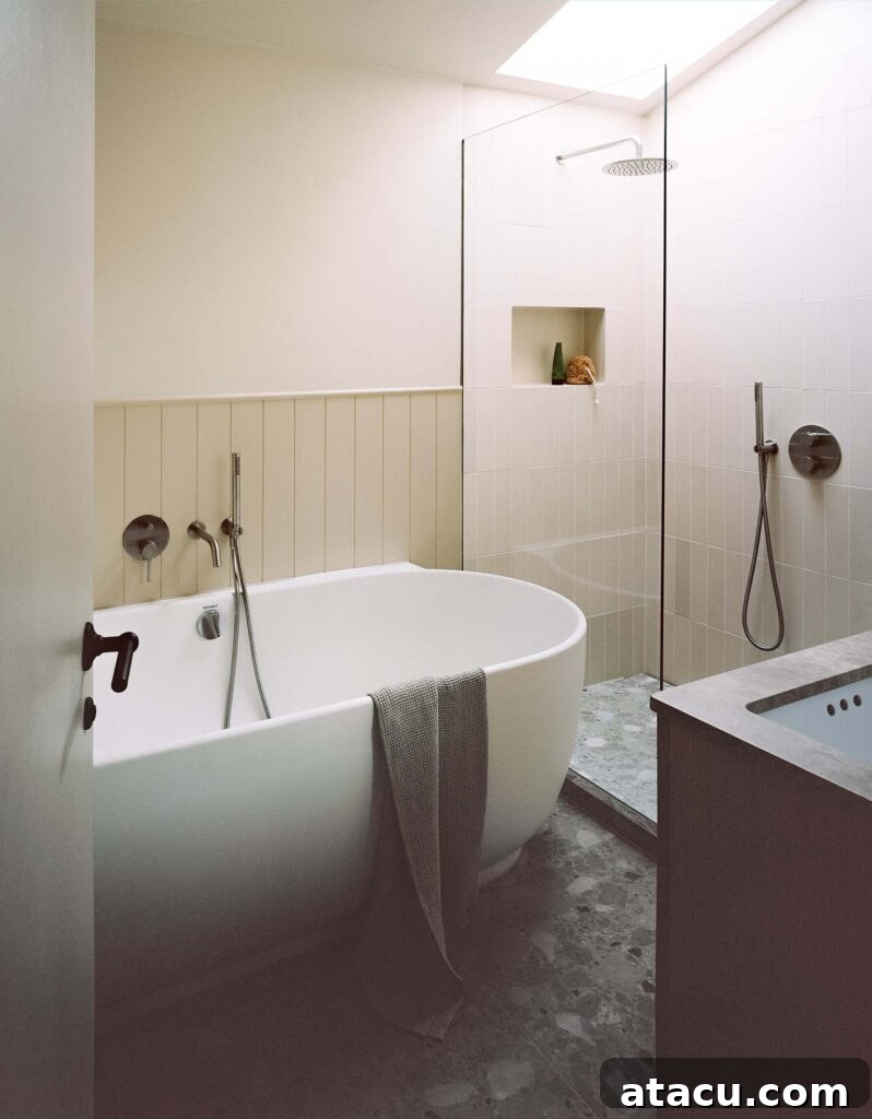 Modern bathroom with soaking tub and walk-in shower under skylight.