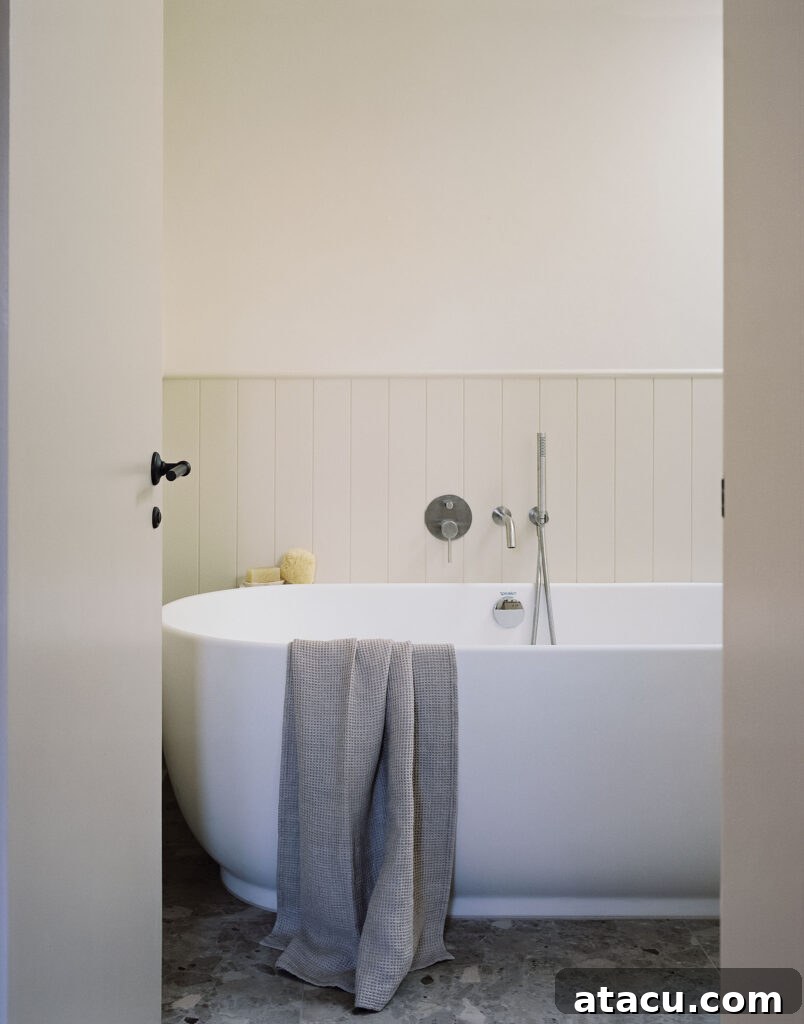 Freestanding white bathtub with towel and wall-mounted fixtures.