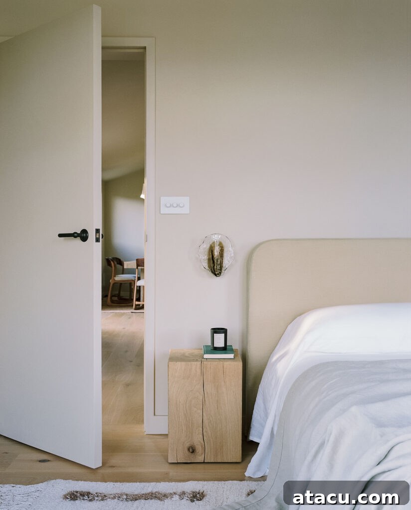 Minimalist bedroom corner with wood nightstand and soft neutral bedding.