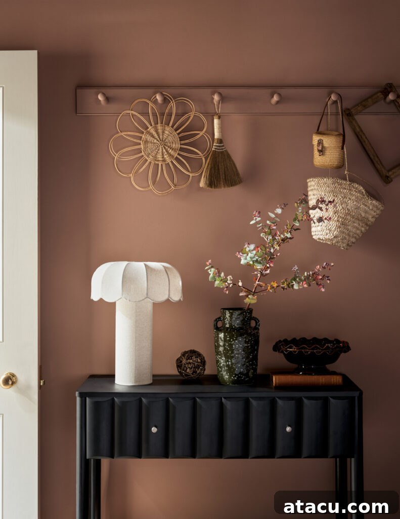Modern black console with ceramic lamp and woven wall decor in a pink-toned entryway.