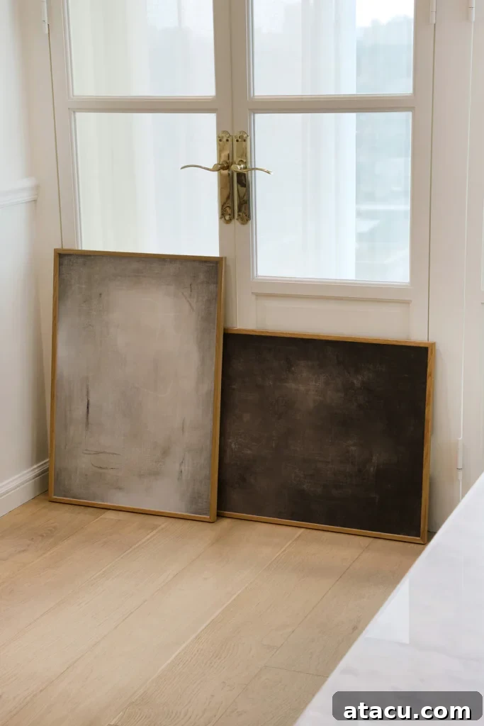 Two minimalist abstract art pieces with wooden frames leaning against white French doors.