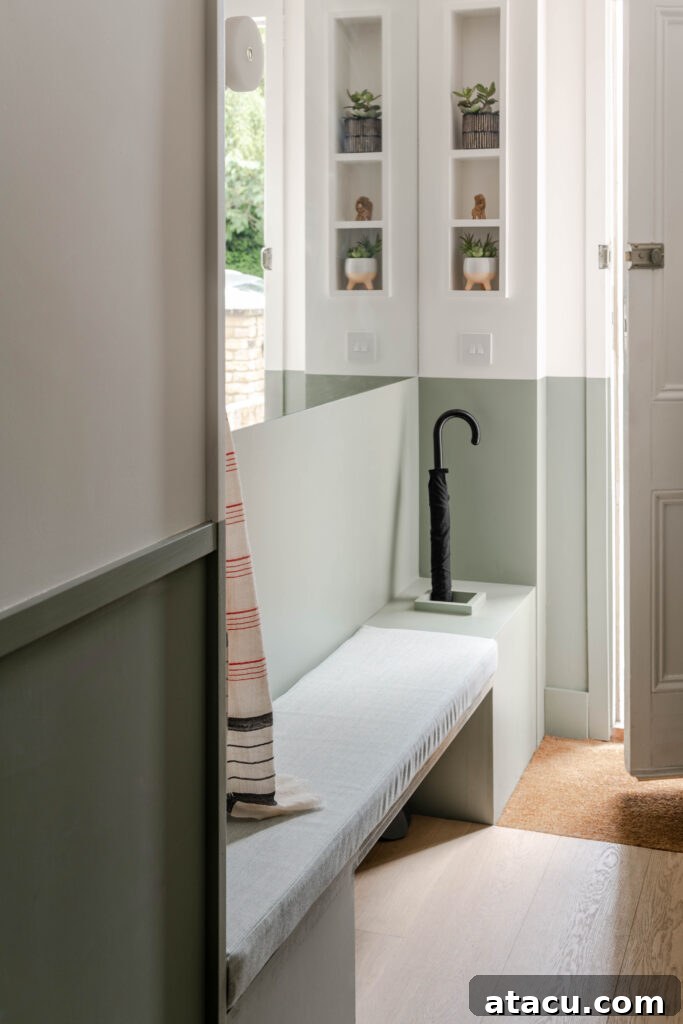 A functional and welcoming entryway featuring stylish sage green bench seating and a minimalist umbrella stand, integrated seamlessly into built-in wall niches.