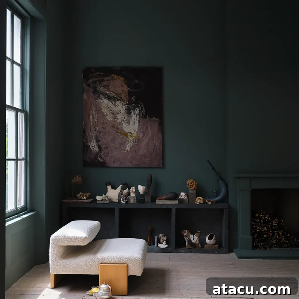 Moody living space with deep green walls painted in Farrow & Ball’s Douter, featuring a sculptural chair and abstract artwork.
