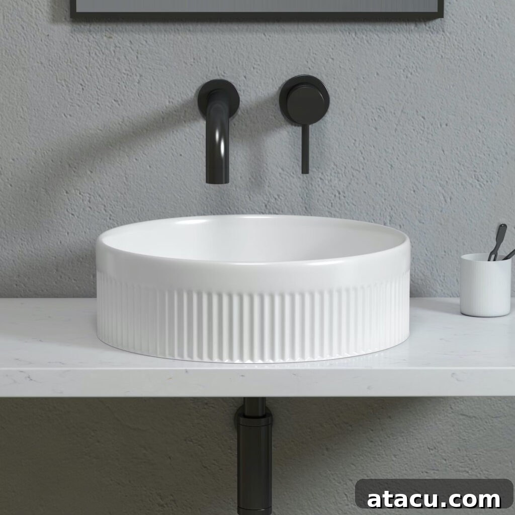 A fluted round countertop basin on a marble worktop with black taps.