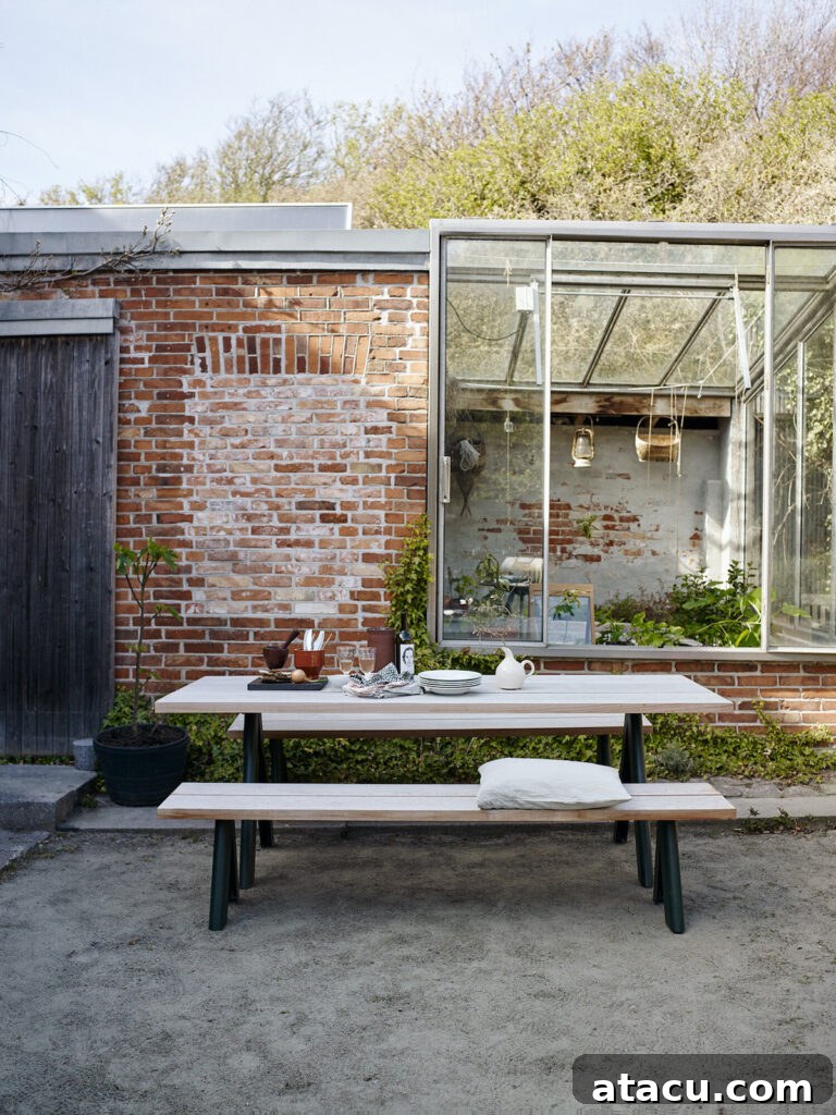 Upgrade Your Outdoors: 10 Best Dining Sets for 2024 5 A robust outdoor dining table accompanied by a sturdy bench, perfect for family meals and relaxed gatherings in the garden.